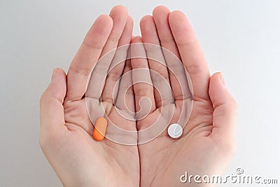 Man hands giving two big pills. White and orange. Make your selection. Health or ill. Stock Photo