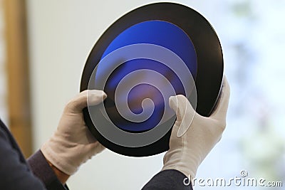 Man hands in gloves holding cobalt blue art glass bowl Editorial Stock Photo