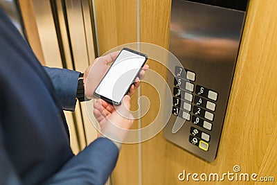 Man hands holding blank screen mobile phone next to elevator control panel Stock Photo