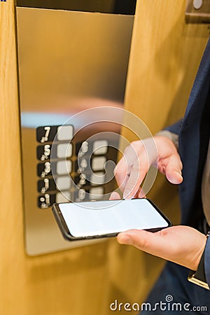 Man hands holding blank screen mobile phone next to elevator control panel Stock Photo