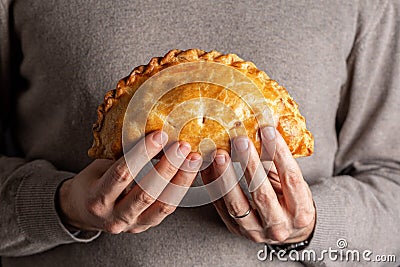 Man hands holding cornish pasty, meat turnover or pie, with filling, beef, carrot Stock Photo