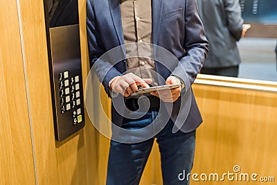 Man hands holding tablet device next to elevator control panel Stock Photo