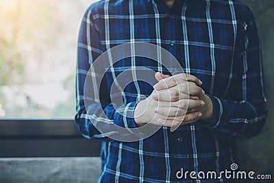 A man hands praying to God over concrete wall with window light Stock Photo