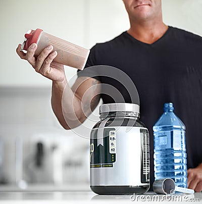 Man, hands and protein shake for nutrition, muscle gain or body mass product and supplement on kitchen table. Hand of Stock Photo