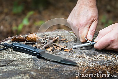 Man hands trying to start a fire with survival tools Stock Photo