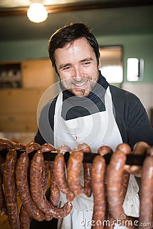 Man hanging homemade raw sausages on wooden stick. Stock Photo