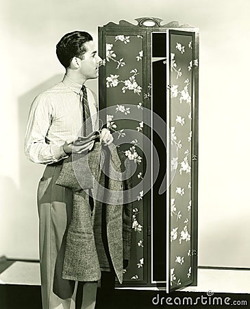 Man hanging up blazer in armoire Stock Photo