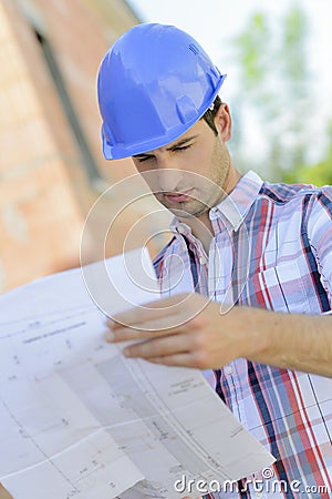 Man in hardhat looking at plans Stock Photo