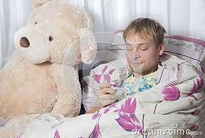 A man has a cold. A man lying in bed with medication and a thermometer. Runny nose,sore throat Stock Photo