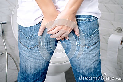 Man has Diarrhea Holding his Butt in the bathroom Stock Photo