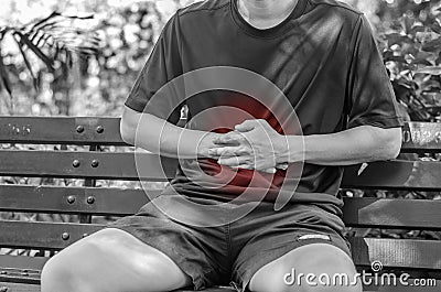 Man has stomachache at park , monochrome photo with red as a symbol for the hardening Stock Photo