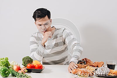 Man having hard choice between healthy and unhealthy food Stock Photo