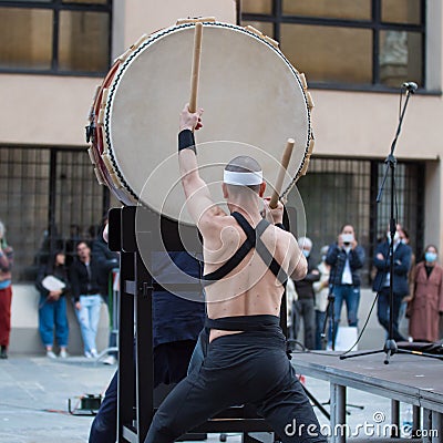 Man with Headband Playing Vertical Drum of Japanese Musical Tradition during a Public Outdoor Event Editorial Stock Photo