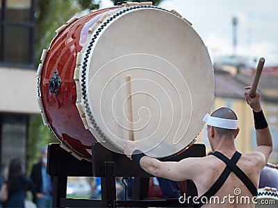 Man with Headband Playing Vertical Drum of Japanese Musical Tradition during a Public Outdoor Event Editorial Stock Photo