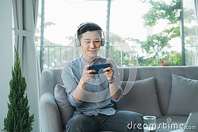 Man headphone mobile sofa game Stock Photo