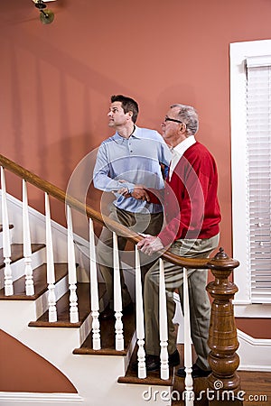 Man helping senior father climb stairs at home Stock Photo