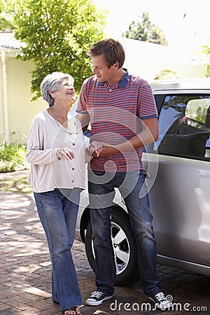 Man Helping Senior Woman Into Car Stock Photo