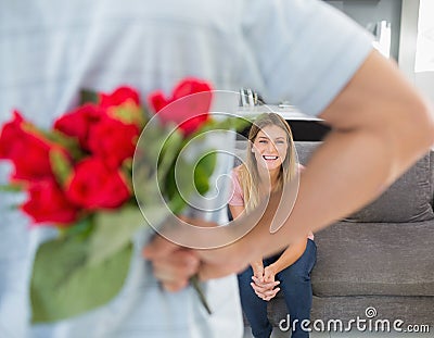 Man hiding bouquet of roses from girlfriend on the couch Stock Photo