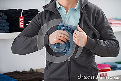 Man Hiding Jeans In Jacket At Store Stock Photo