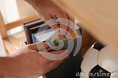 Man hiding money in book indoors. Financial savings Stock Photo