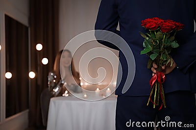 Man hiding roses for his beloved woman in restaurant at romantic dinner Stock Photo