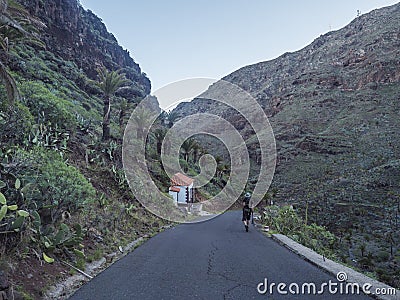 Man hiker figure at Guarimiar village road. At hiking trail through Barranco de Guarimiar Gorge. Green mountain canyon Stock Photo
