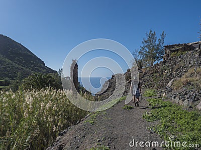 Man hiker at footpath of hiking trail Tasartico to Playa GuiGui beach, Barranco de Guigui Grande ravine with cacti Stock Photo