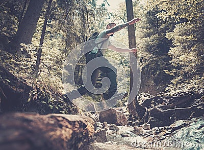 Man hiker jumping across stream Stock Photo