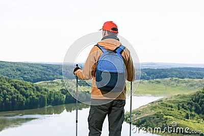 Man hiker observing the the green valley with lake and thinking. Stock Photo