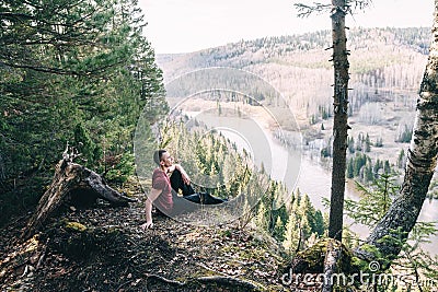 A man hiker sitting on a cliff edge enjoying scenic view Stock Photo