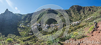 Man hiker watching at scenic landscape with Imada village at hiking trail Barranco de Guarimiar Gorge. Green mountain Stock Photo
