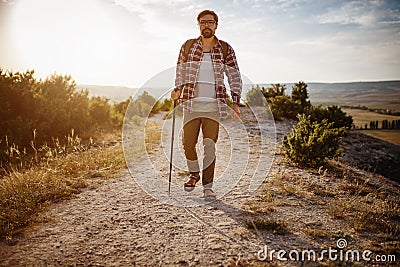 Man hiking in the mountains using pole and looking away Stock Photo