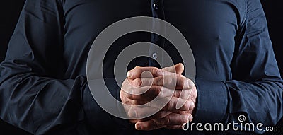 A man with his fingers interlocked on black Stock Photo