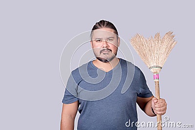 A man in his 30s holding an old broom. A househusband doing the the house cleanup. Cleanliness concept Stock Photo