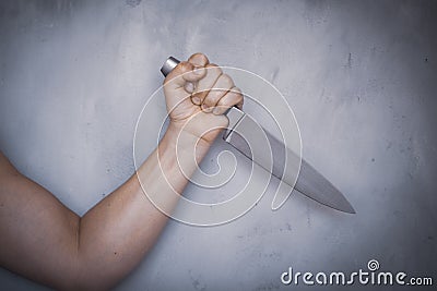 Man hold knife - aggression. Big kitchen knife in man hand. Large kitchen knife in a man`s hand, on a gray background Stock Photo