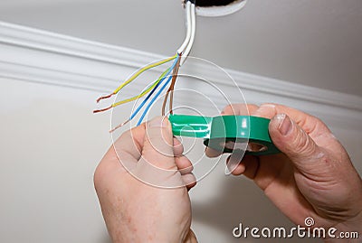 Man is holding adhesive tape in his hands. Electrical insulator for light bulb. Maintenance repair works in the flat. Restoration Stock Photo