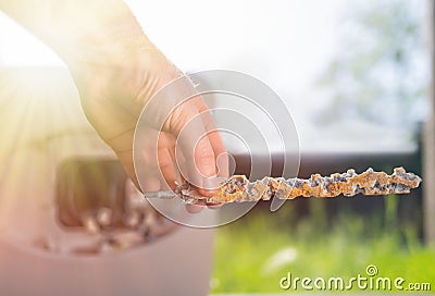 A man holding a anode damaged from corrosion. In the background the boiler and a view of the lawn. Close up. Light Stock Photo