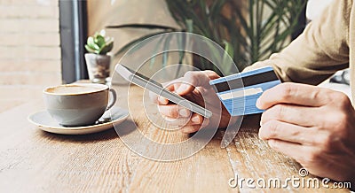 Man holding credit card and using smart phone in a cafe, travel, online shopping, ecommerce, internet banking, finance and freelan Stock Photo