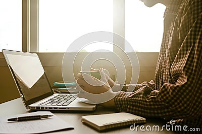 A man holding a cup of coffee and working on laptop in offic Stock Photo