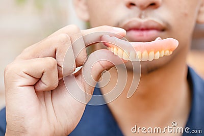 A man is holding dentures in his hands. Removable dentures flexible. False teeth Stock Photo