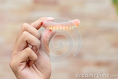 A man is holding dentures in his hands. Removable dentures flexible. False teeth Stock Photo