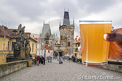 Man holding glass of light beer with view of Charles bridge in Prague Stock Photo