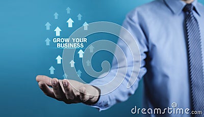 Man holding Grow Your Business words with growth arrows. Stock Photo