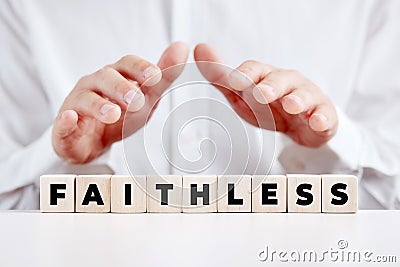 Man holding his hands over the wooden cubes with the word faithless. Disbelief or unfaithful Stock Photo