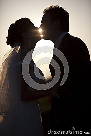 Man holding kissing woman silhouettes evening park Stock Photo