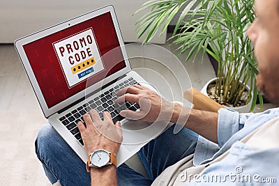 Man holding laptop with activated promo code indoors, closeup Stock Photo