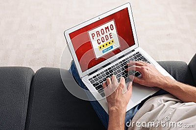 Man holding laptop with activated promo code on sofa, above view Stock Photo