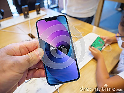 Man holding new iPhone 13 at the Apple Store with its colorful wallpaper Editorial Stock Photo