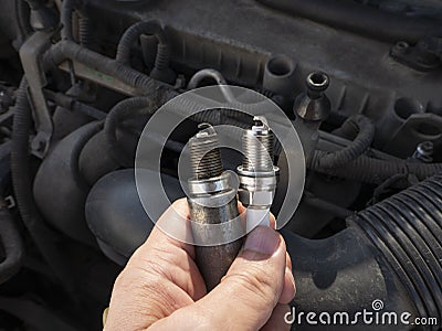 Man Holding old and new car spark plugs on engine background Stock Photo