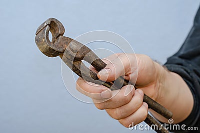 A man is holding old tongs in his hand. A rusty metal hand tool Stock Photo